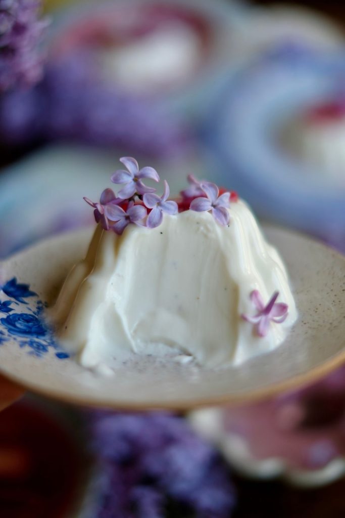 Creamy vanilla bean panna cotta topped with lilacs and rhubarb