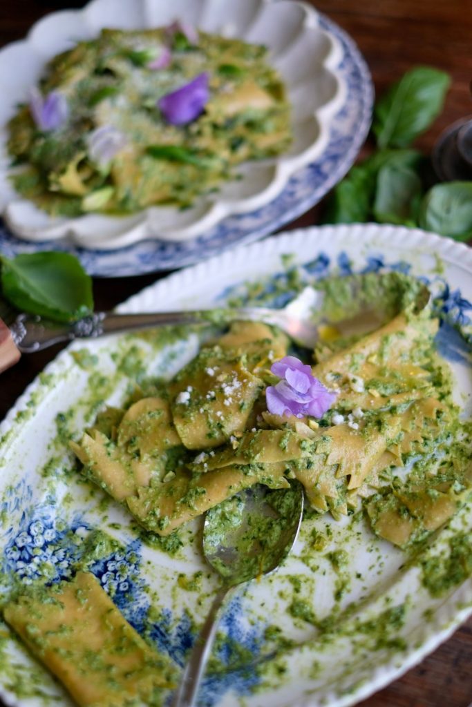 pesto fazzoletti pasta in a serving platter garnished with an edible flower