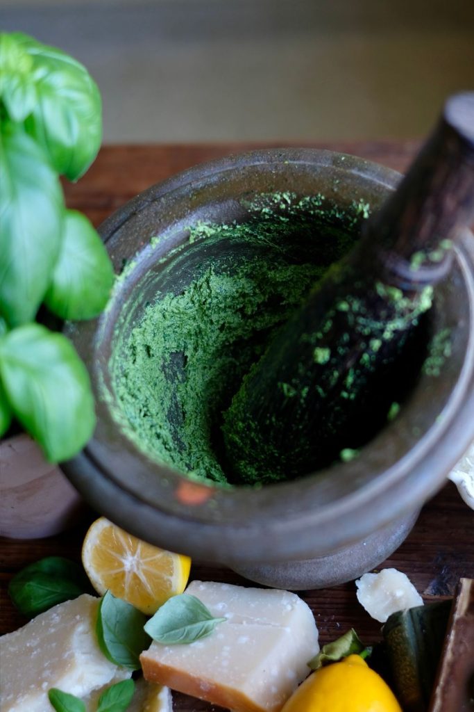 Grinding the basil in a pestle and mortar for pesto