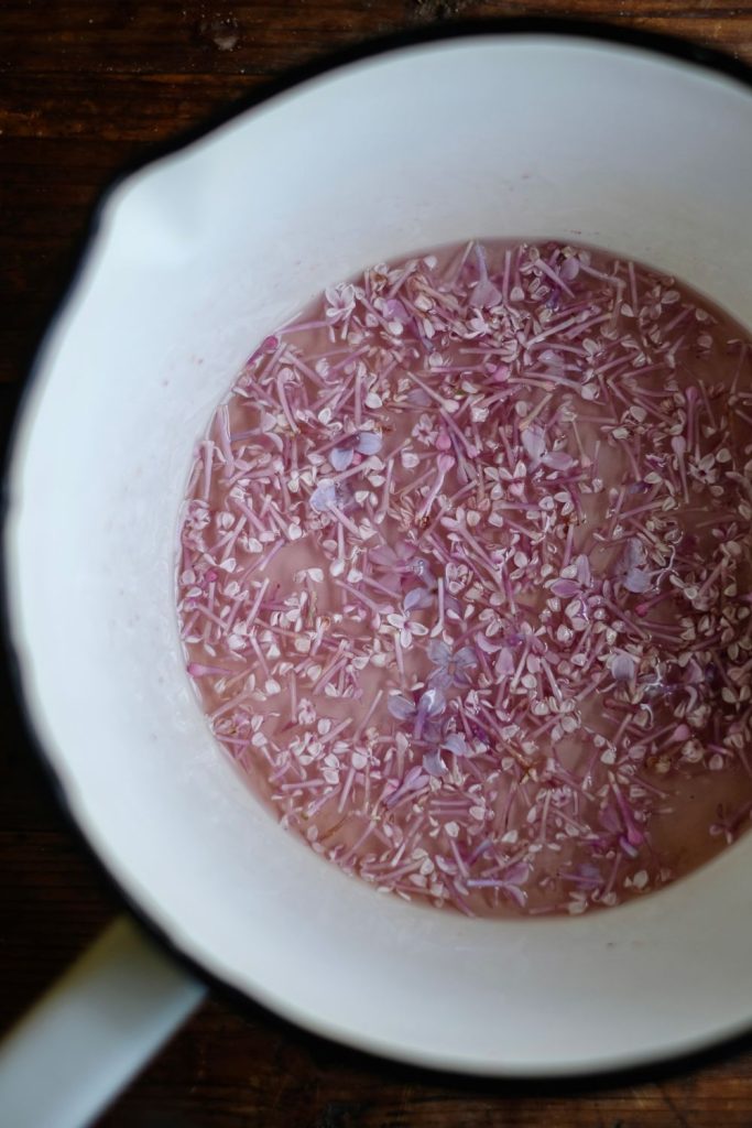 steeping lilac blossoms in a saucepan for lilac syrup