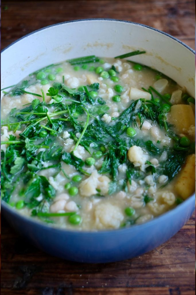 Spring pea soup in a dutch oven with vegetables and herbs