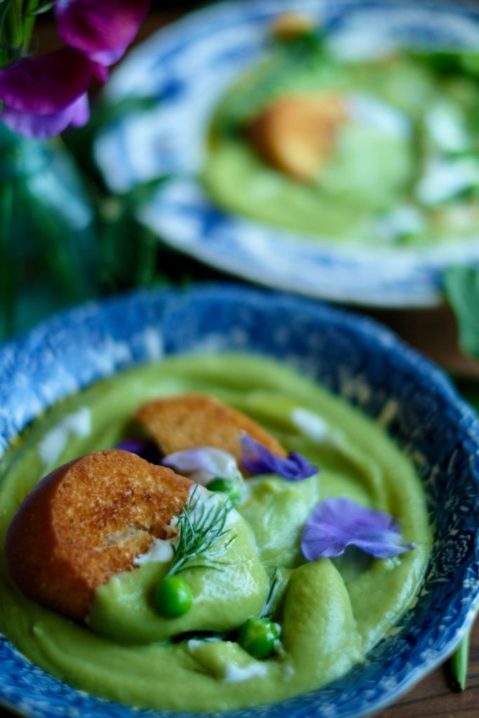 Spring Pea Soup topped with croutons, edible flowers, and a dill frond