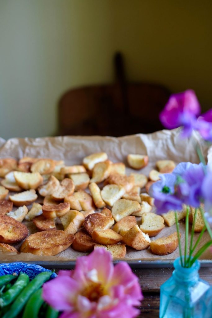 Slice baguette pieces lined on a baking sheet after they are baked