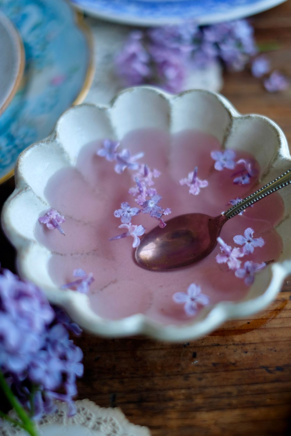 Simple Syrup in a bowl with a spoon and lilac blossoms